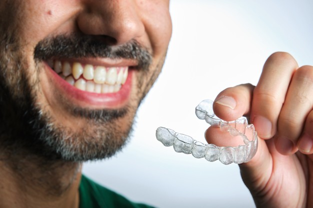 man smiling holding clear aligners