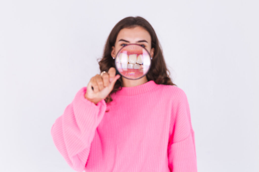 person with a magnifier showing teeth